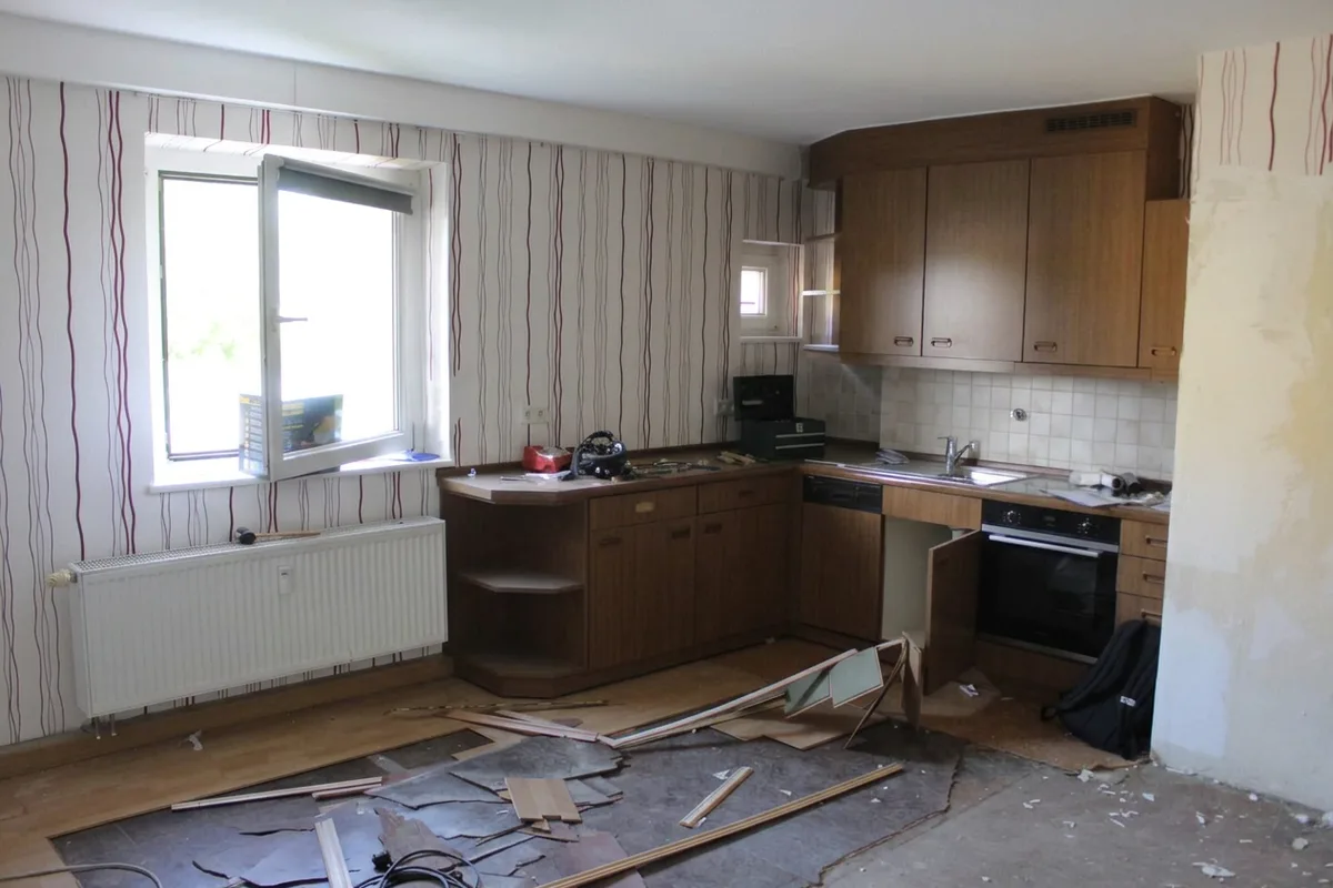 Küche vor der Renovierung mit alten Holzküchenzeilen und rausgerissener Arbeitsfläche